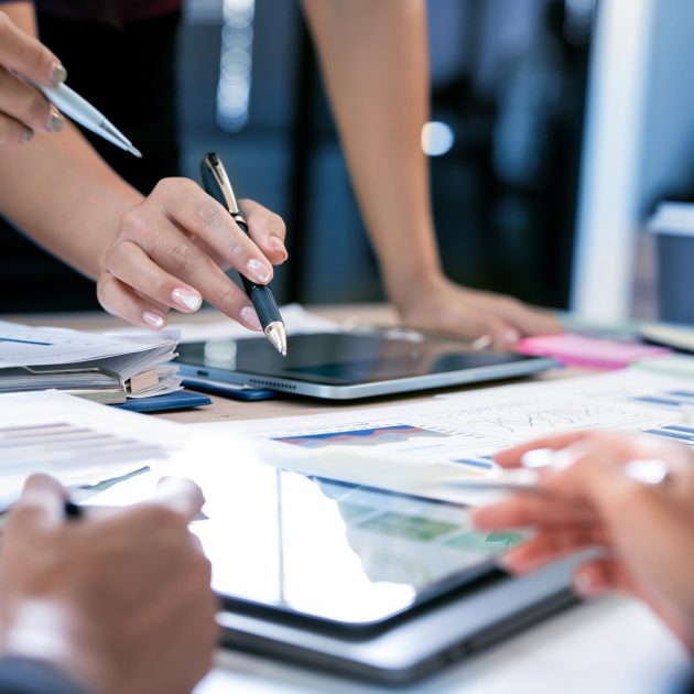 Close-up of business people hands pointing at data charts and us